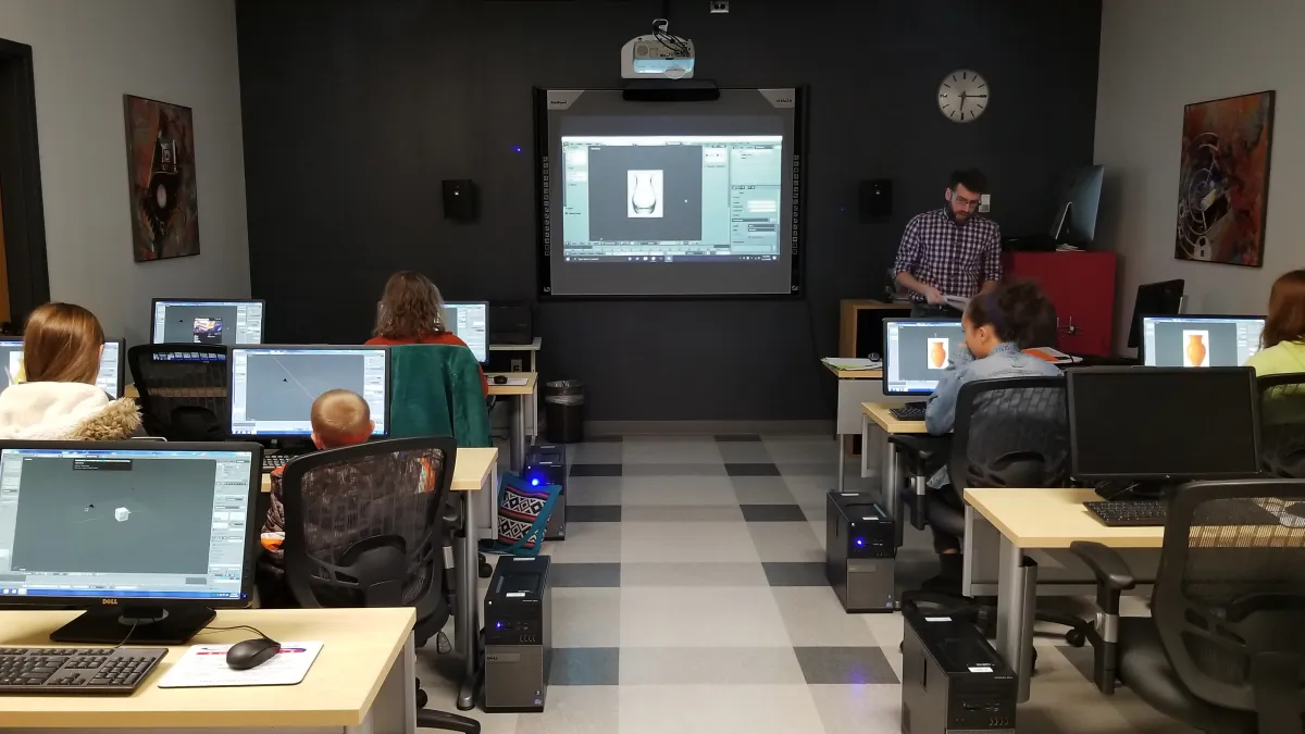 Technology Training Lab showing people sitting in front of desktop computers watching a demonstration at the front of the room