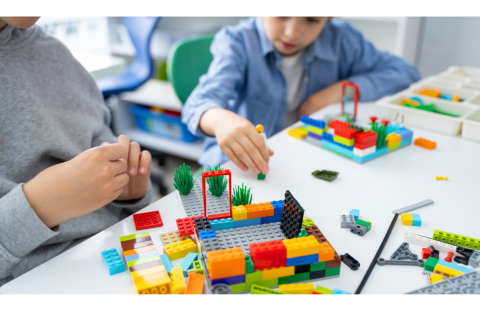 close up shot of two children sitting at a table playing with legos