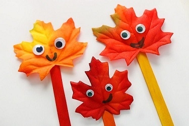 Paper Autumn colored leaves pasted on a popsicle stick with google eyes