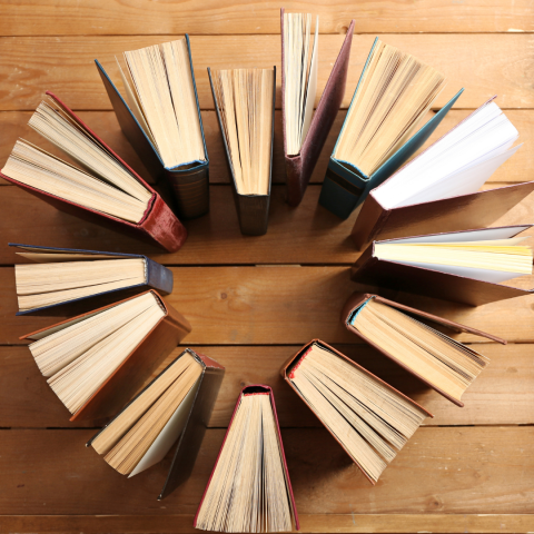 many books arranged with their spines facing inwards so that form a heart in the middle of them