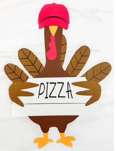 Turkey paper craft wearing a hat and holding a pizza box.