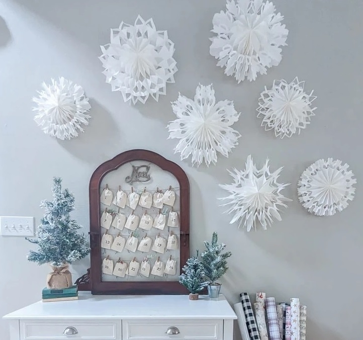 Seven large, white, 3-d paper snowflakes on wall above desk