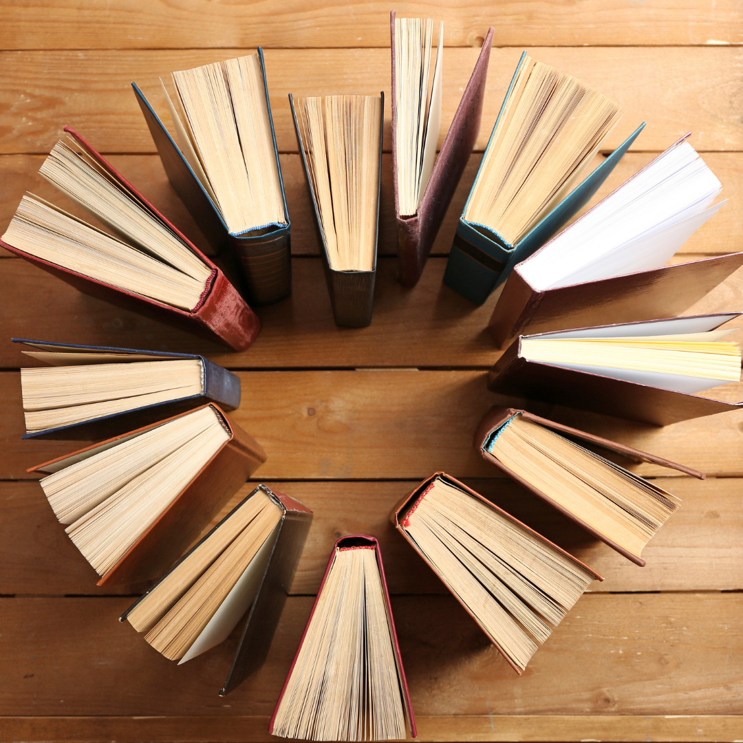 many books arranged with their spines facing inwards so that form a heart in the middle of them